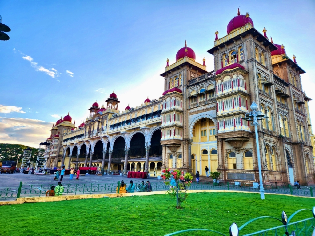 a view of the mysore palace from a side angle showing its many red domes, arches and pillars
