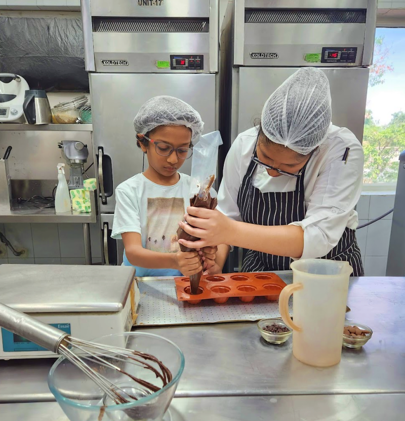 child learning with hotel chef how to make cupcakes